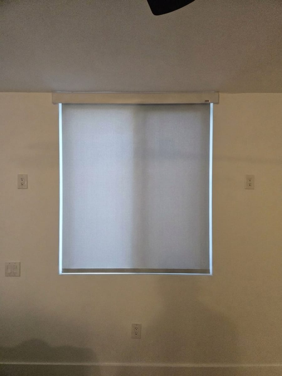 The same window fitted with a roller shade, daylight coming through the fabric.